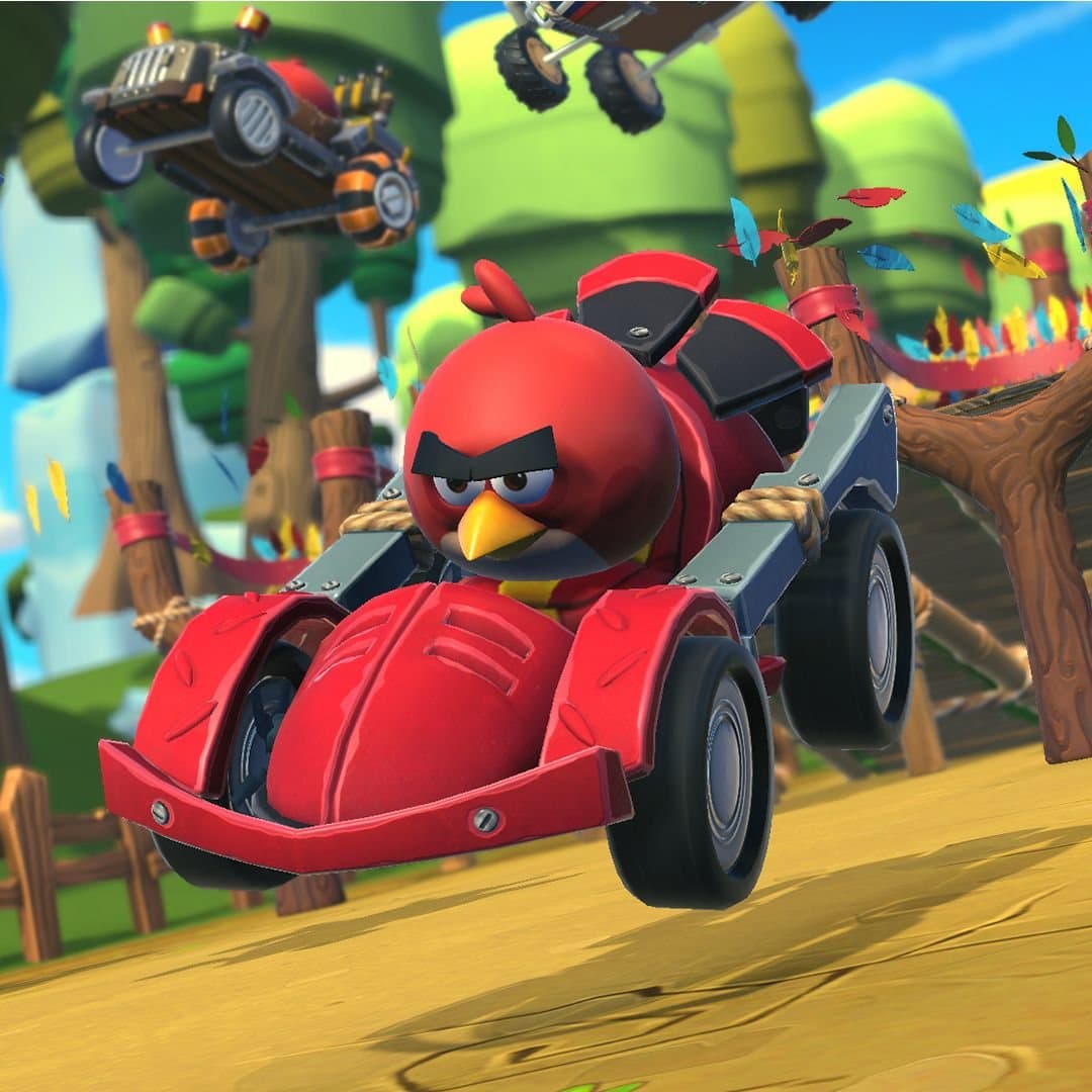 Red mid-air in his red kart on a Feathered Woodlands track, feathers scattering behind him as rival karts tumble in the background.