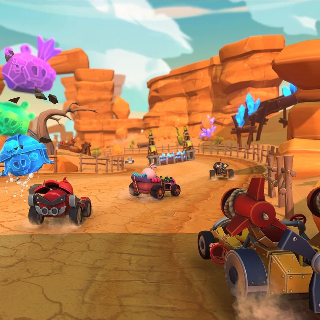 Karts racing through Rocky Canyons past piggy structures and crystal formations, with destroyed pig heads bursting in the foreground.